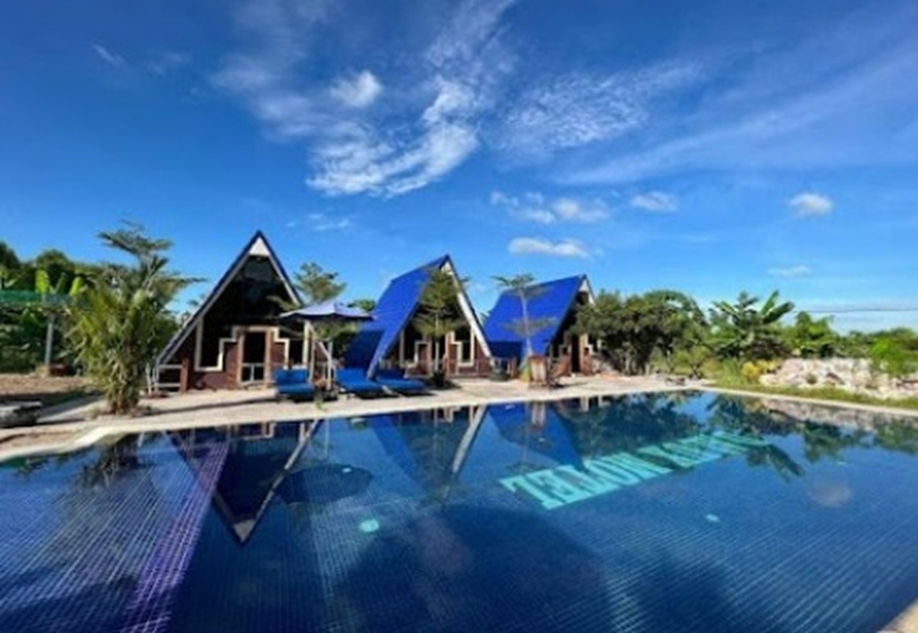 Un resort con piscina cristalina, varias cabañas tipo bungalow y un entorno tropical.