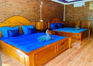 A room with two wooden beds, each with a blue bedspread and pillows, and a swan decoration on the bed. - Dalux Motel (Banan)