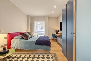 Een moderne slaapkamer met een bed, bureau en televisie.