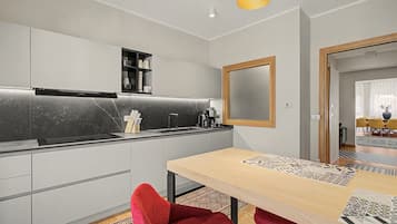 Eine moderne Küche mit Backofen, Spüle und Kaffeemaschine. Ein Essbereich mit Tisch und Stühlen ist ebenfalls vorhanden.