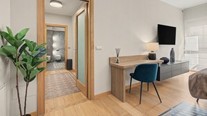 A modern living room with a wooden desk, a blue chair, a flat-screen TV mounted on the wall, and a large window. - Aluméa – Charming and Wellness Retreat in Central Aosta with Mountain Views (Aosta)