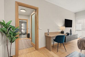 Ein modernes Wohnzimmer mit einem Holztisch, einem blauen Sessel, einem wandmontierten Flachbildfernseher und einem großen Fenster.