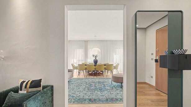 A modern interior with a dining area, a green sofa, and a mirror. - Aluméa – Charming and Wellness Retreat in Central Aosta with Mountain Views (Aosta)