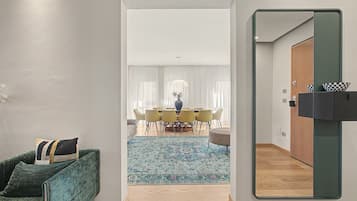 Un intérieur moderne avec un coin repas, un canapé vert et un miroir.