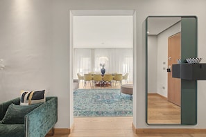 A modern interior with a dining area, a green sofa, and a mirror.