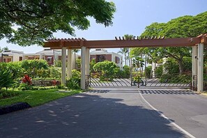 A gated entrance with a pergola, a sign reading "Mauna Lani Terrace," and a view of residential buildings in the background. - Upgraded Oceanfront Condo at Mauna Lani Terrace (Kamuela)