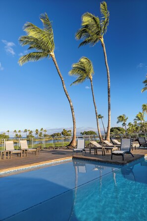 A poolside area with lounge chairs and palm trees. - Upgraded Oceanfront Condo at Mauna Lani Terrace (Kamuela)