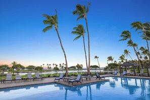 A poolside area with lounge chairs and palm trees against a clear sky. - Upgraded Oceanfront Condo at Mauna Lani Terrace (Kamuela)