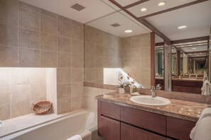 Ein modernes Badezimmer mit einer Badewanne, einem Waschbecken und einem großen Spiegel.