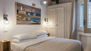 Un dormitorio con una cama, un cuadro de una escena costera y dos luces fijadas a la pared.