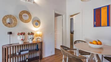 A dining area with a round table, wicker chairs, a wooden console table with decorative items, and wall-mounted mirrors.