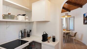 A modern kitchen with white cabinetry, a built-in stove, and a dining area with a table and chairs.