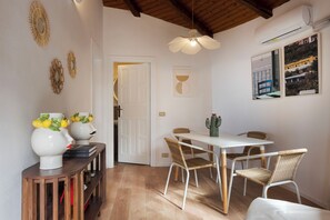 Un comedor con una mesa blanca, sillas de mimbre y un ventilador de techo.