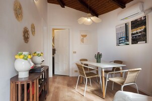 A dining area with a white table, wicker chairs, and a ceiling fan.