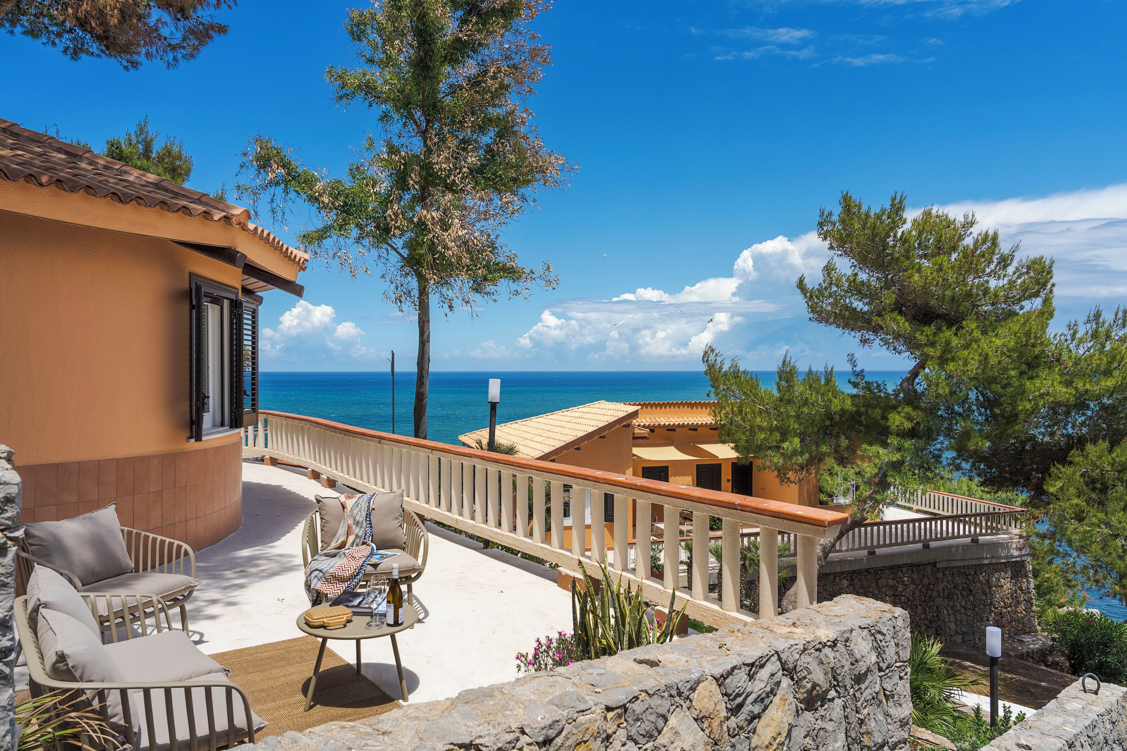 A coastal property with a terrace, outdoor seating, and a view of the sea.