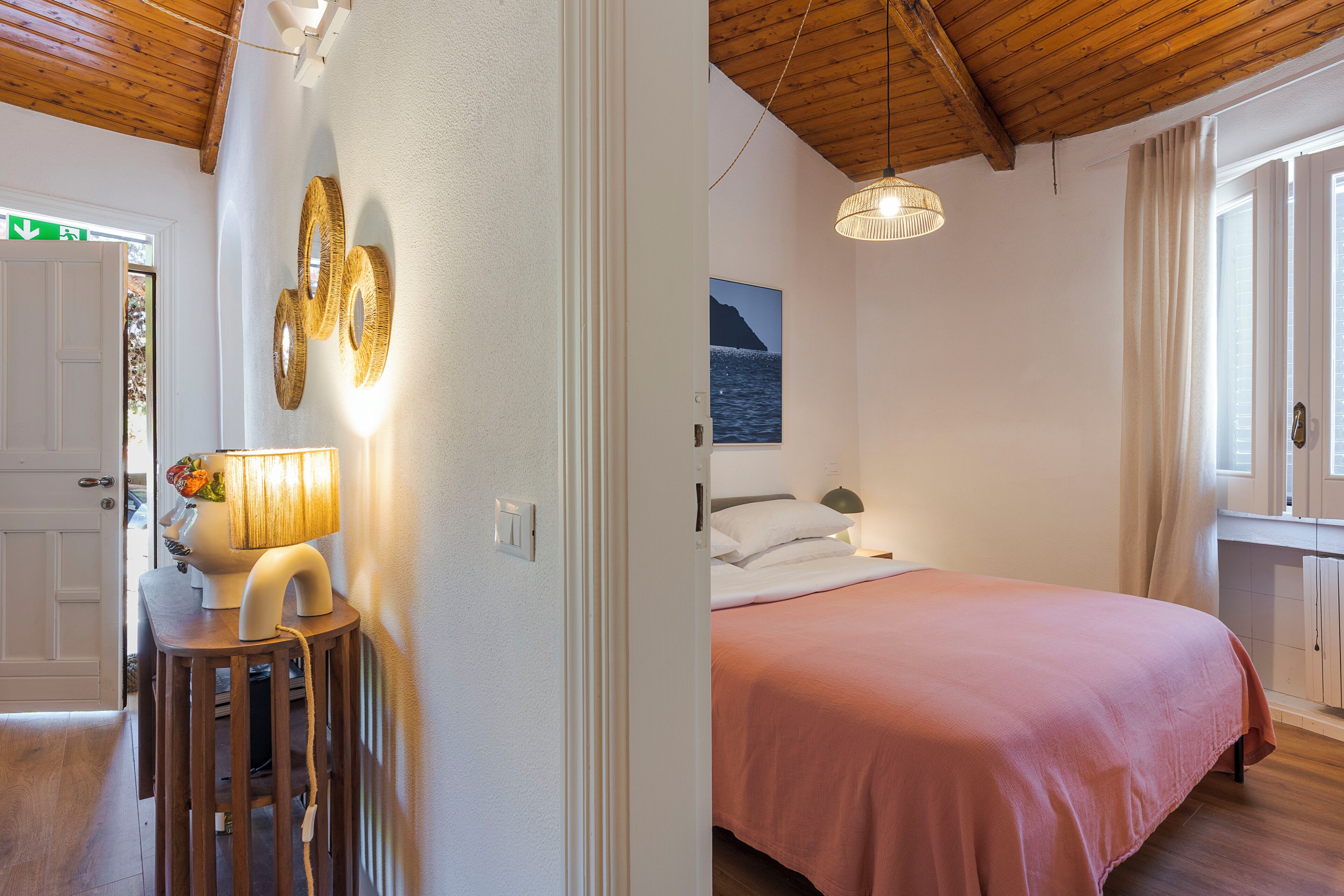 Een slaapkamer met een bed, nachtkastje, lamp en een schilderij aan de muur.