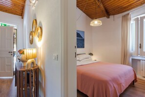 Un dormitorio con cama, mesita de noche, lámpara y un cuadro en la pared.