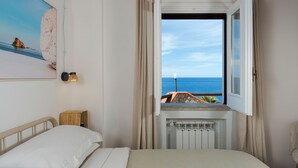 Un dormitorio con una cama, una ventana con cortinas, un radiador y un cuadro en la pared.