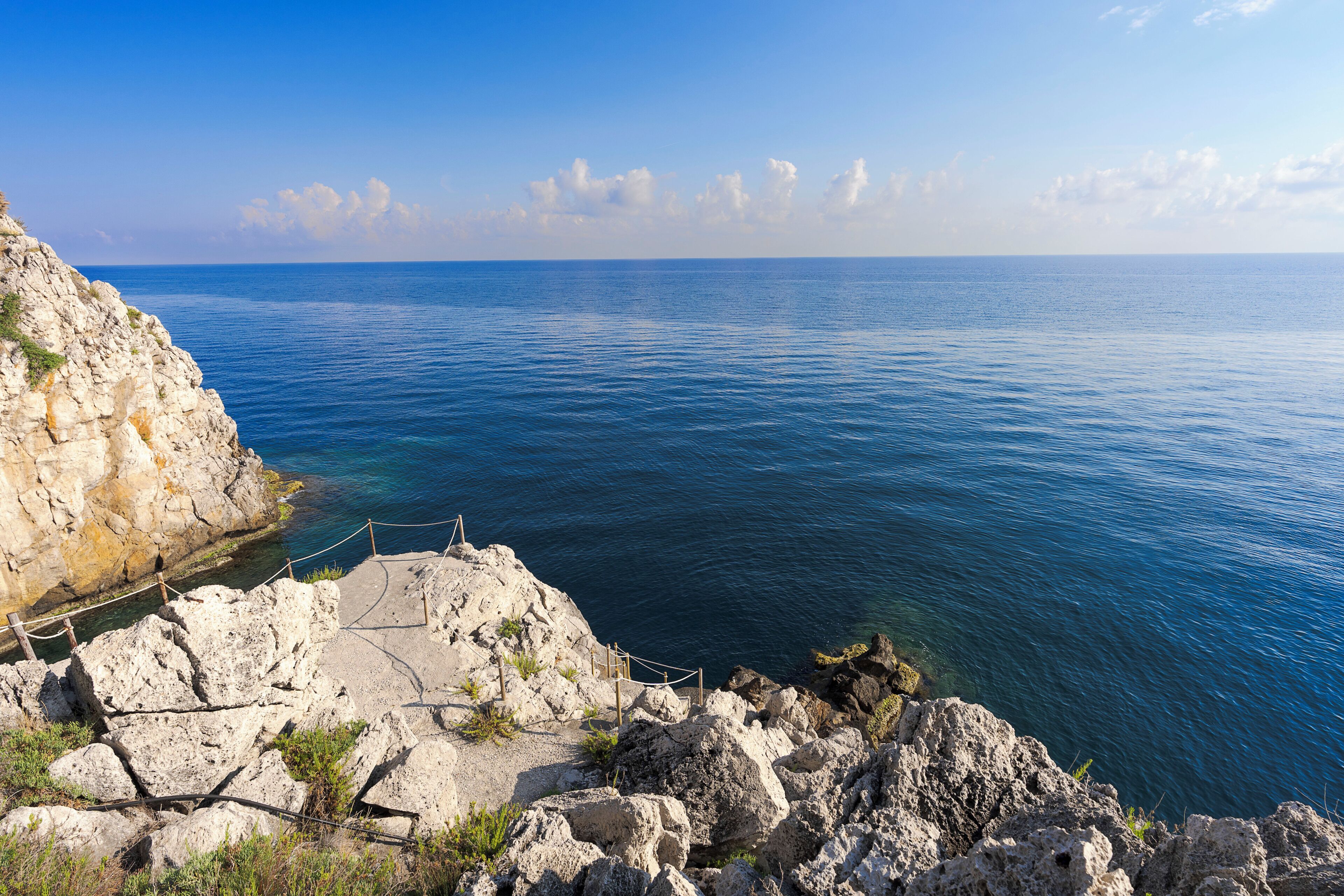 A coastal landscape with rocky terrain and a clear view of the sea.