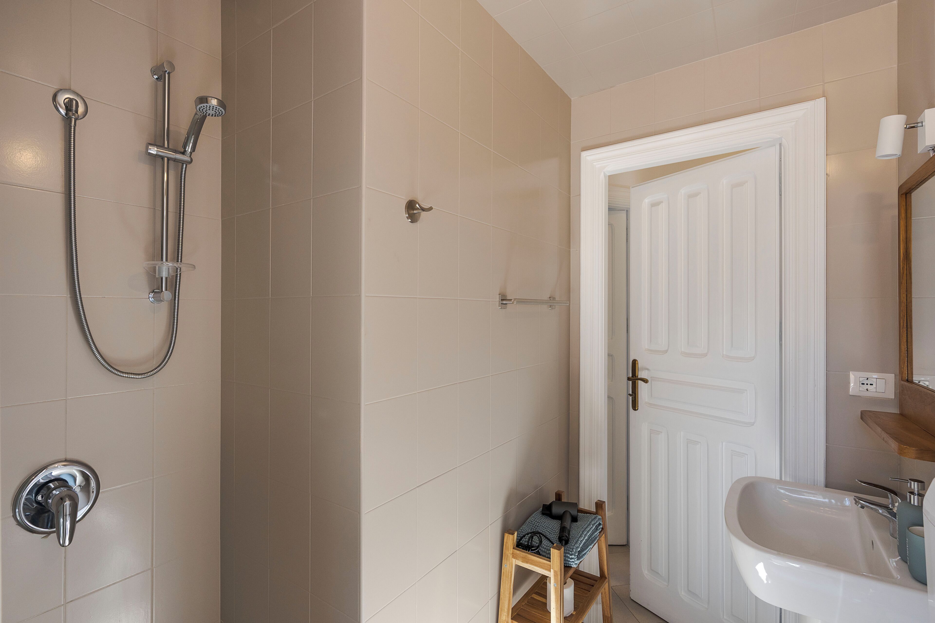 Une salle de bain avec une douche, un lavabo et une porte.