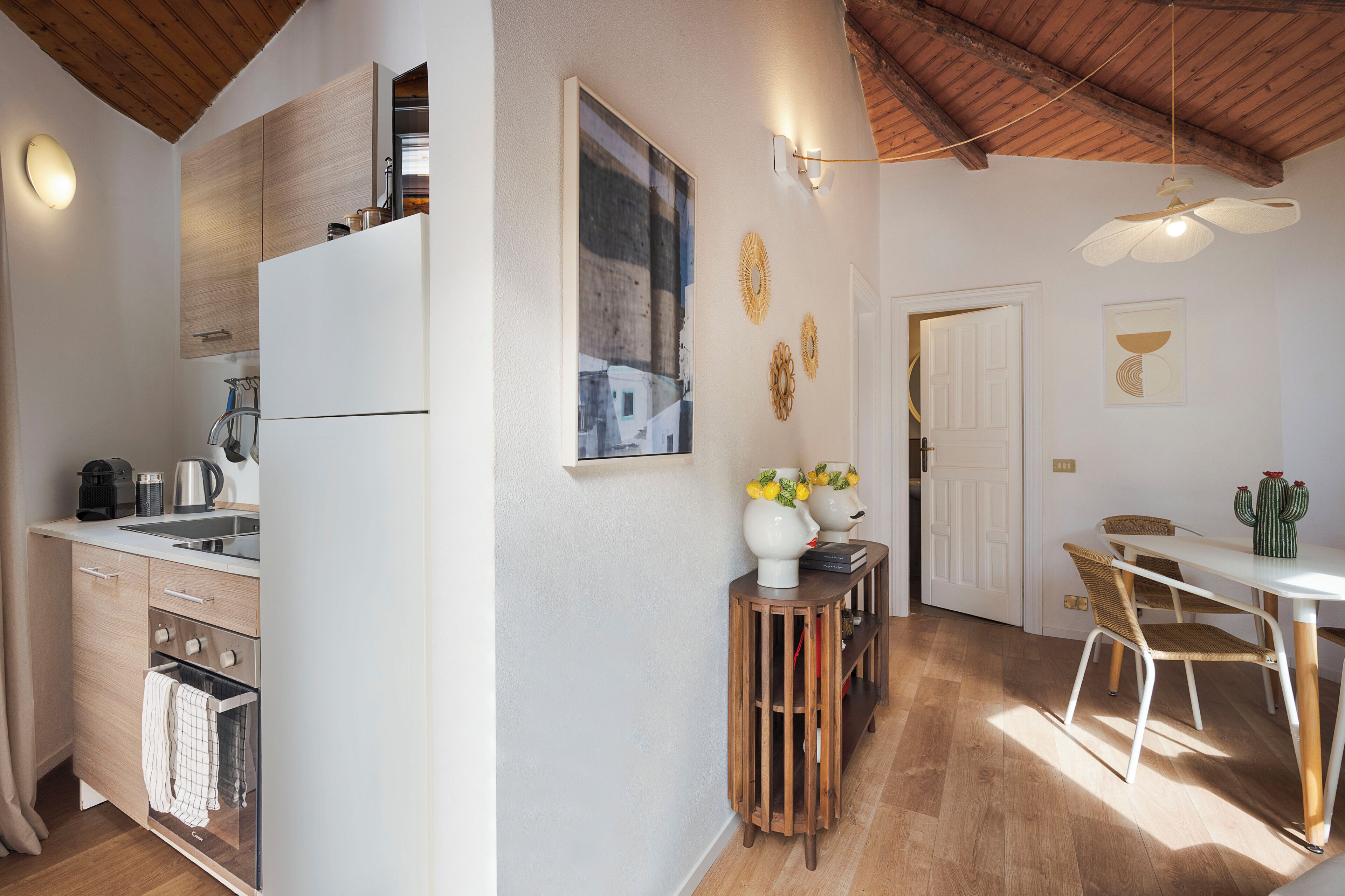 A modern kitchen with a built-in refrigerator, wooden cabinets, and a dining area with a table and chairs.