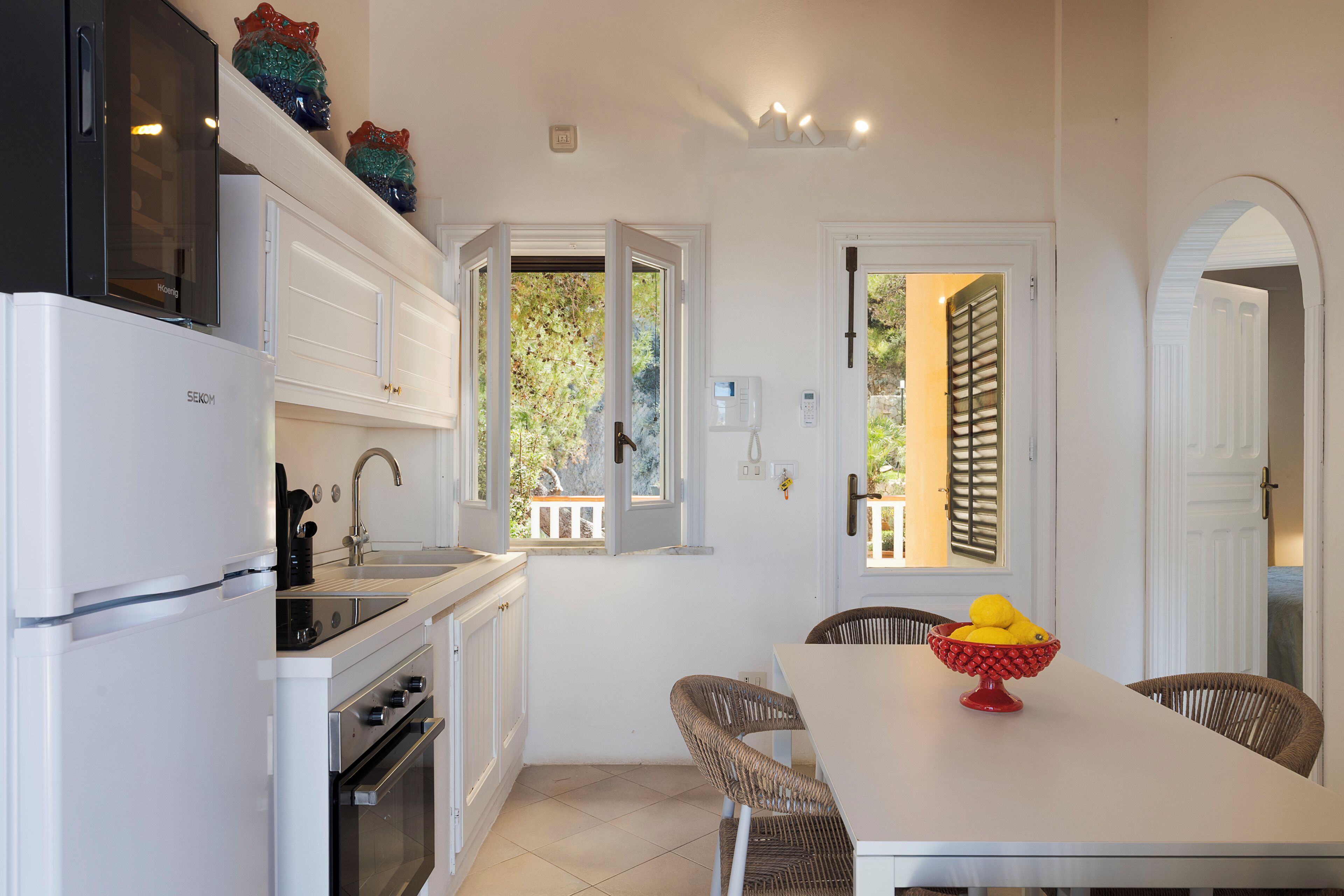 A compact kitchen with white cabinetry, a built-in oven, and a dining area with a table and chairs.