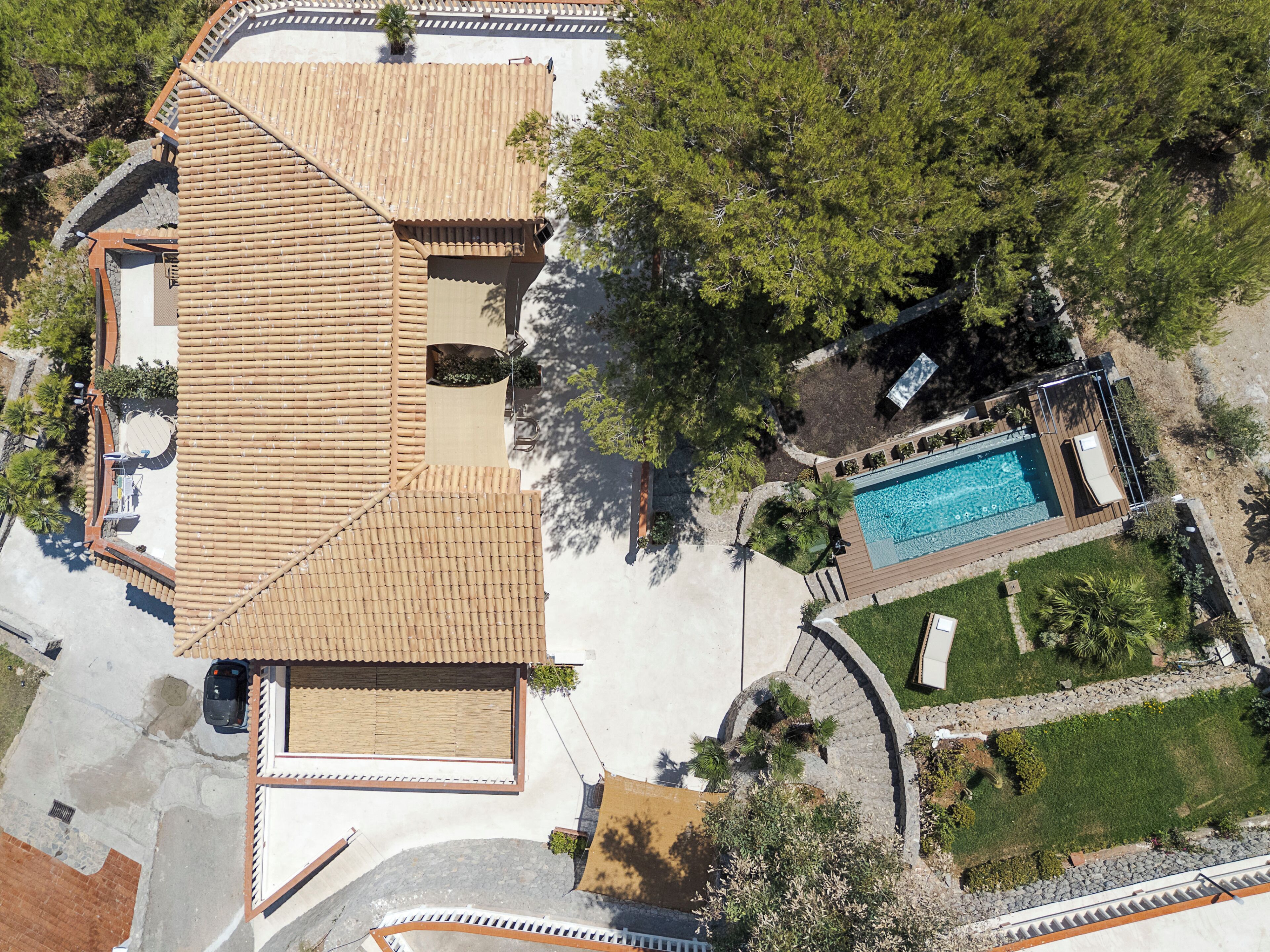 An aerial view of a residential property with a swimming pool, a covered patio, and a fenced yard.