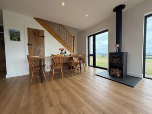 Eine moderne Küche mit Holzböden, einem Esstisch mit Stühlen, einer Holztreppe und einem Kamin mit Blick.