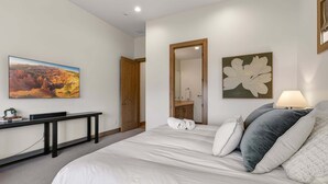 A bedroom with a bed, a desk, a mirror, and a painting on the wall. - Clubhouse Close Villa, golf, min 90 day stay (Heber City)