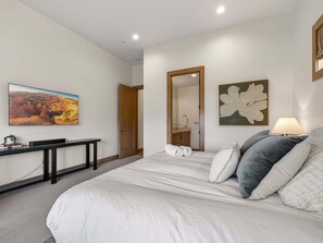Ein Schlafzimmer mit einem Bett, einem Schreibtisch, einem Spiegel und einem Bild an der Wand.
