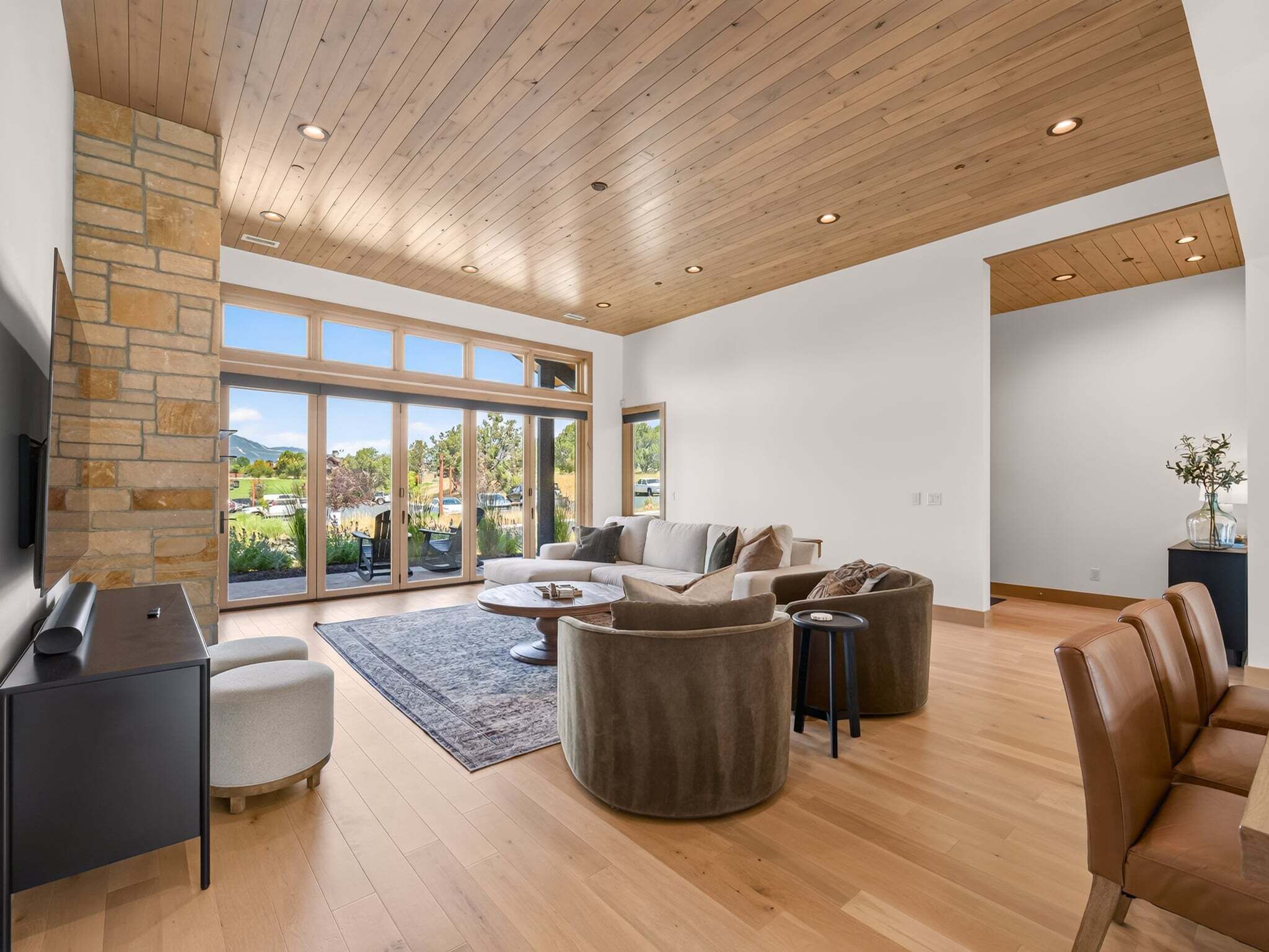 A spacious living room with a stone fireplace, a large sofa set, and a television.