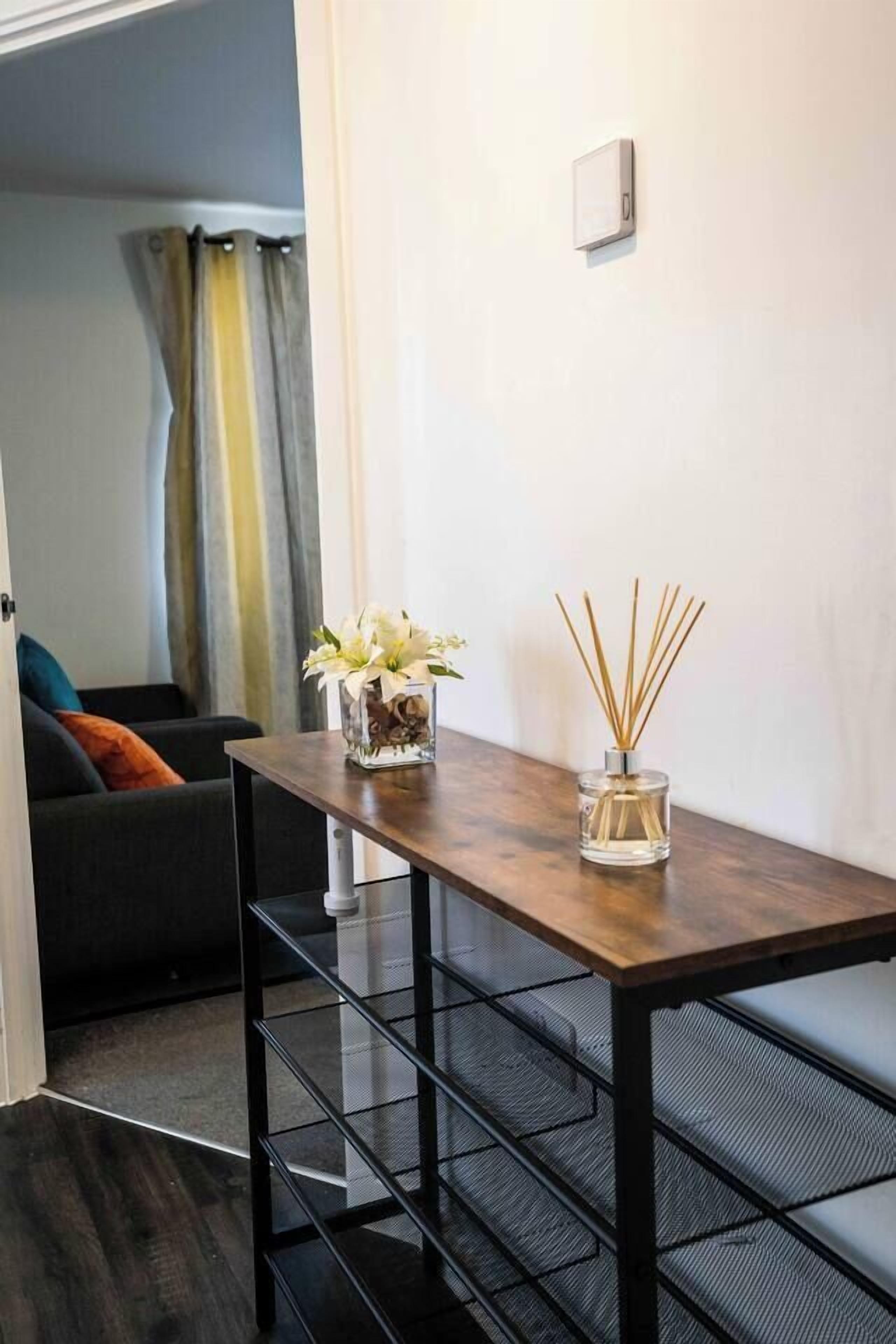 A small dining area with a wooden table, two glass candle holders, and a black metal bench.