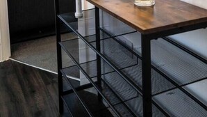 Ein kleiner Essbereich mit einem Holztisch, zwei Glaswindlichtern und einer schwarzen Metallbank.