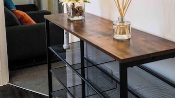 A small dining area with a wooden table, two glass candle holders, and a black metal bench.