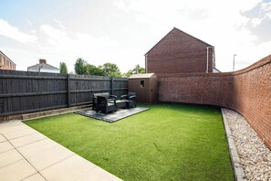 A backyard with a patio area, a brick wall, and a wooden fence. - 3-Bed Serviced Home | Ensuite | Work Desk| Bilston (West Midlands)