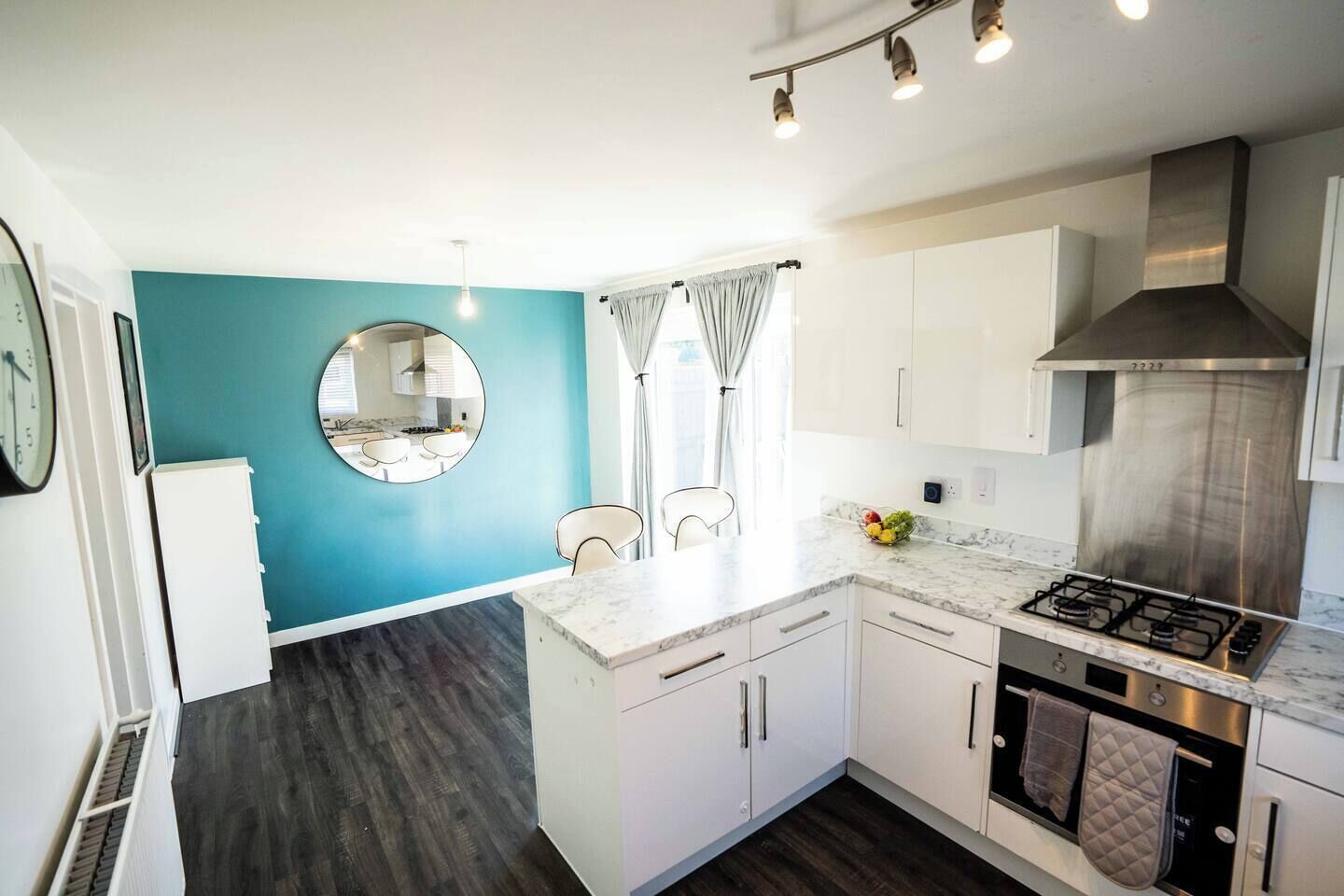 A modern kitchen with a central island, white cabinetry, and a blue accent wall.