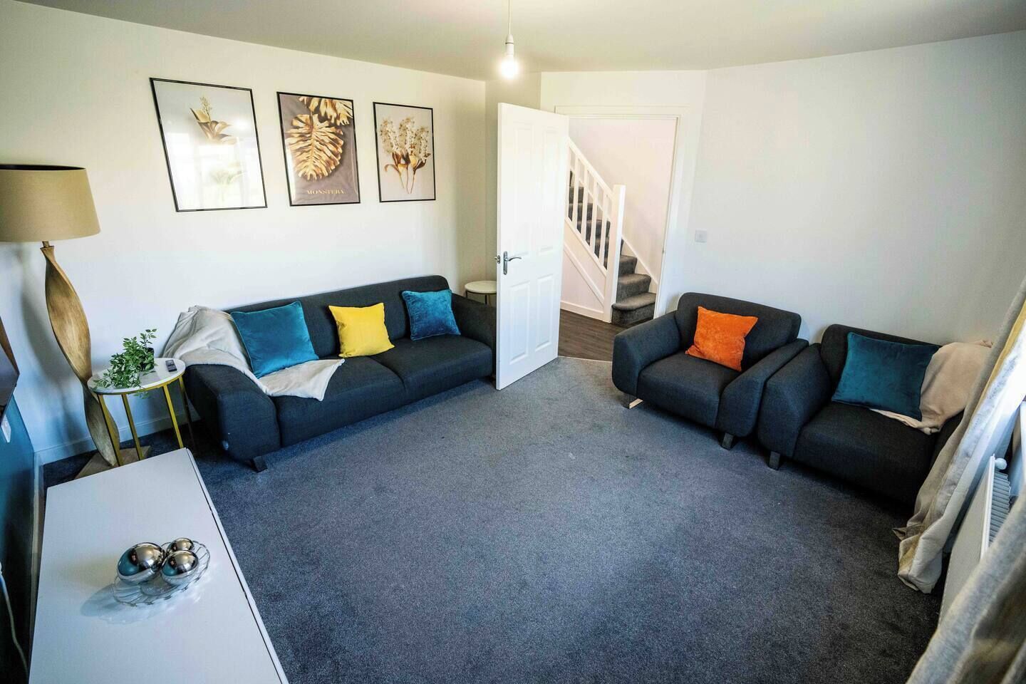 Ein Wohnzimmer mit zwei Sofas, einem Couchtisch und einer Lampe. Eine Treppe führt zu einer weiteren Ebene.