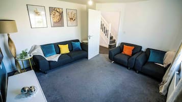 A living room with two sofas, a coffee table, and a lamp. There is a staircase leading to another level.