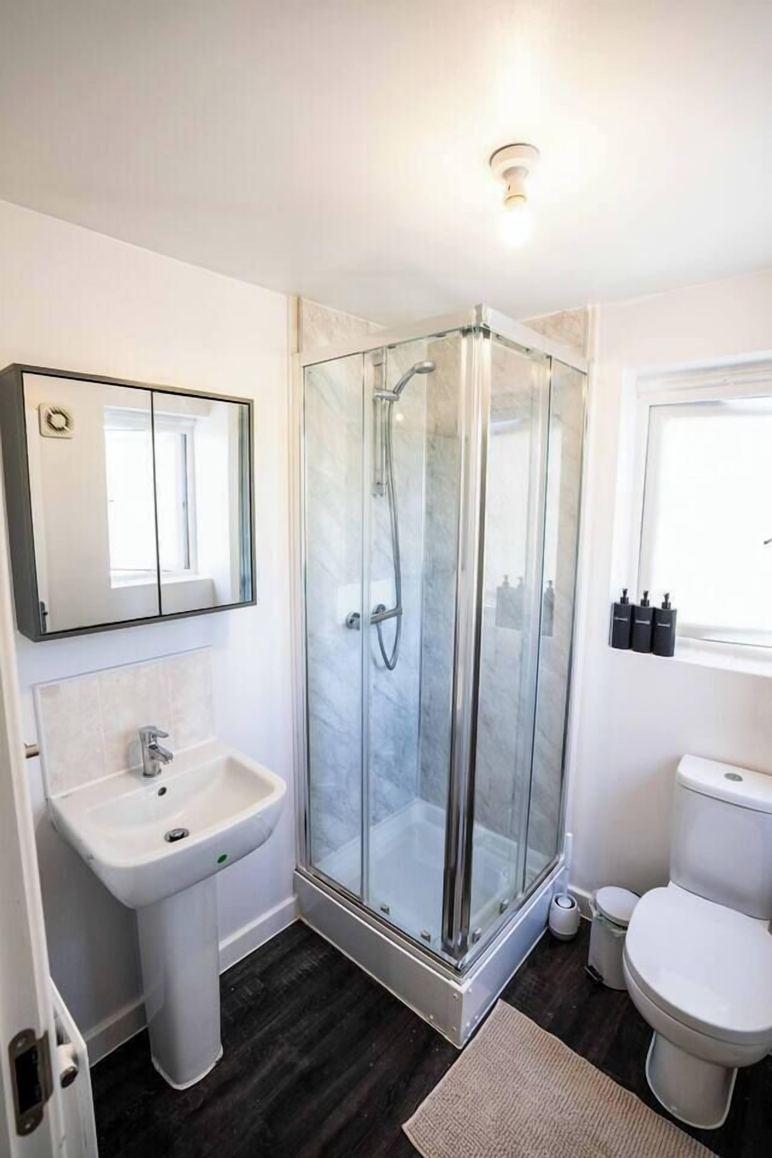 A bathroom with a glass-enclosed shower, a sink, and a toilet.