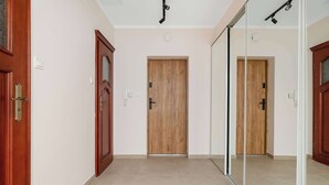 A hallway with wooden doors, a glass partition, and a ceiling-mounted light fixture. - Charming Studio for 4 | Cosiness and Comfort (Bielsko-Biała)