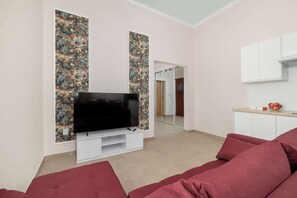 Una sala de estar moderna con un televisor de pantalla plana, un sofá rojo y una zona de cocina con armarios y encimera.
