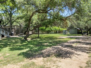 A backyard with a covered patio, a fenced area, and a small shed.