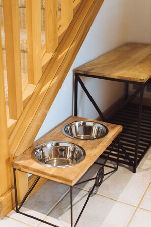 A wooden dog feeding station with two metal bowls on a tiled floor. - 3 Min to Sand | Family Fun + Bunk Room | Sleeps 9 (Cloverdale)