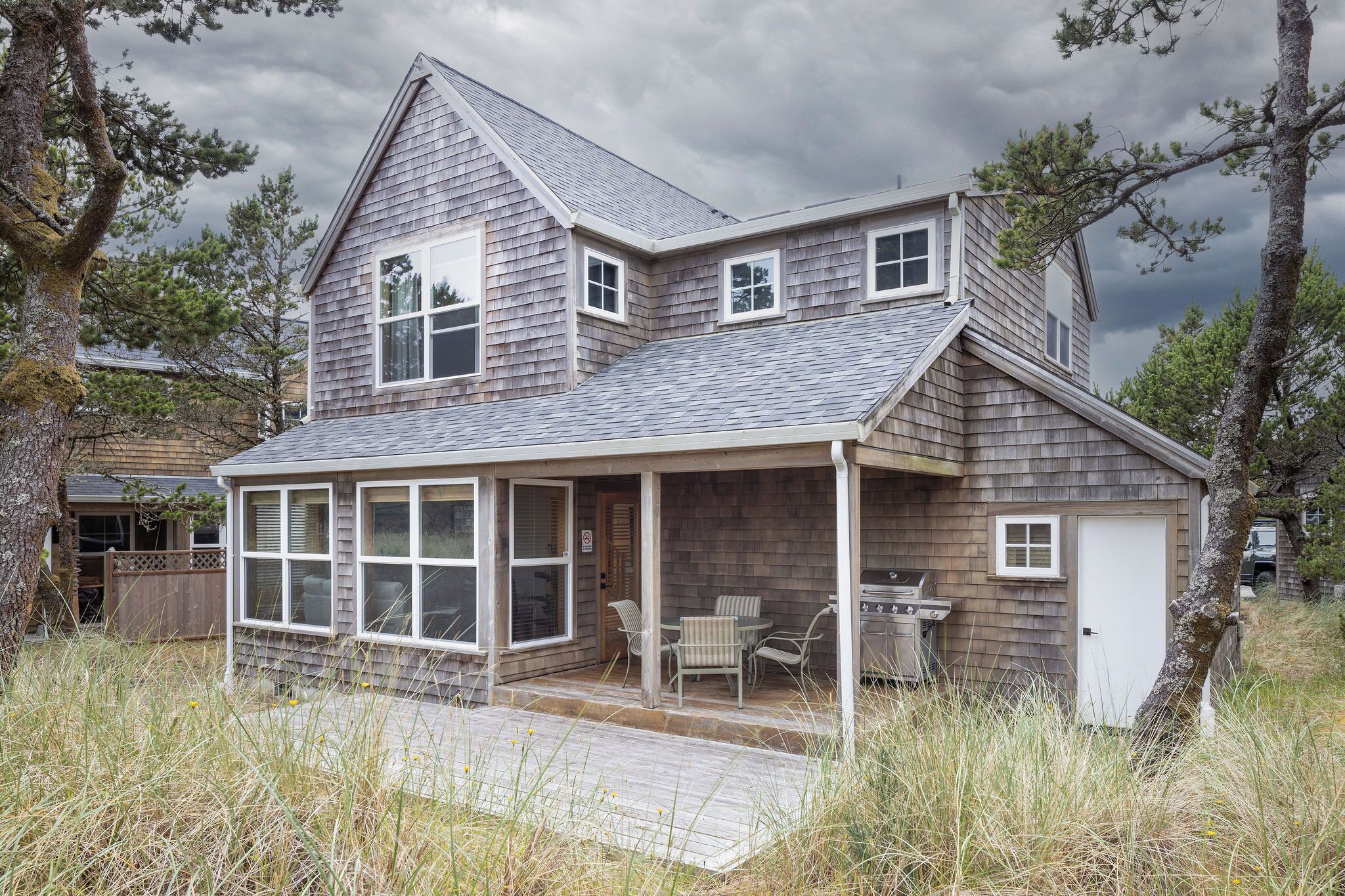 A two-story house with a covered porch, a garage, and a small outdoor grill area.