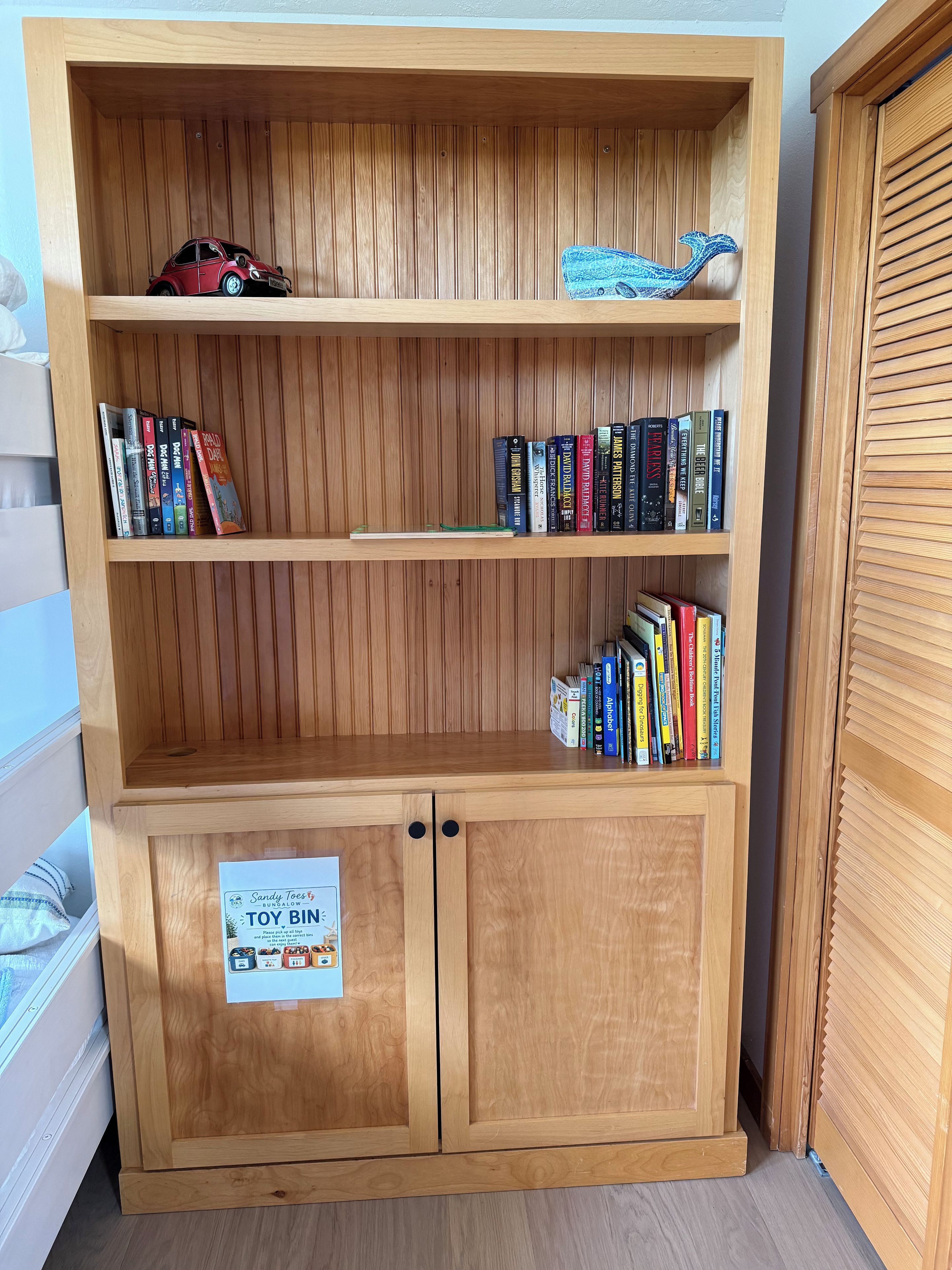A wooden bookshelf with multiple shelves containing books and a toy car.