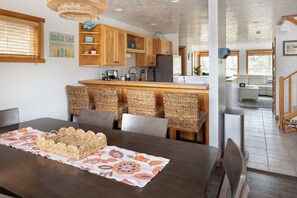 Eine moderne Küche mit Holzschränken, einer integrierten Kochinsel und einem Essbereich mit Korbstühlen.