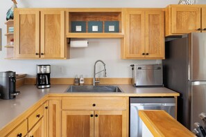 A kitchen with wooden cabinets, a stainless steel sink, a coffee maker, a toaster, and a dishwasher. - 3 Min to Sand | Family Fun + Bunk Room | Sleeps 9 (Cloverdale)