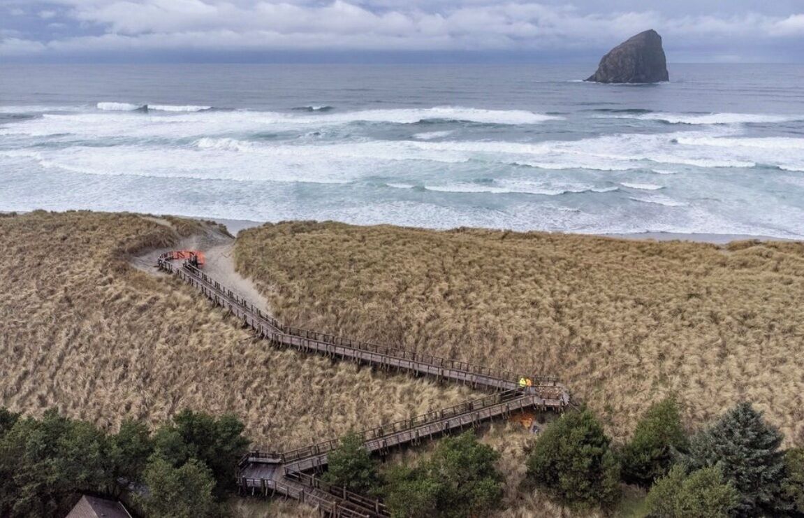 A coastal area with a wooden boardwalk leading to a rocky outcrop.