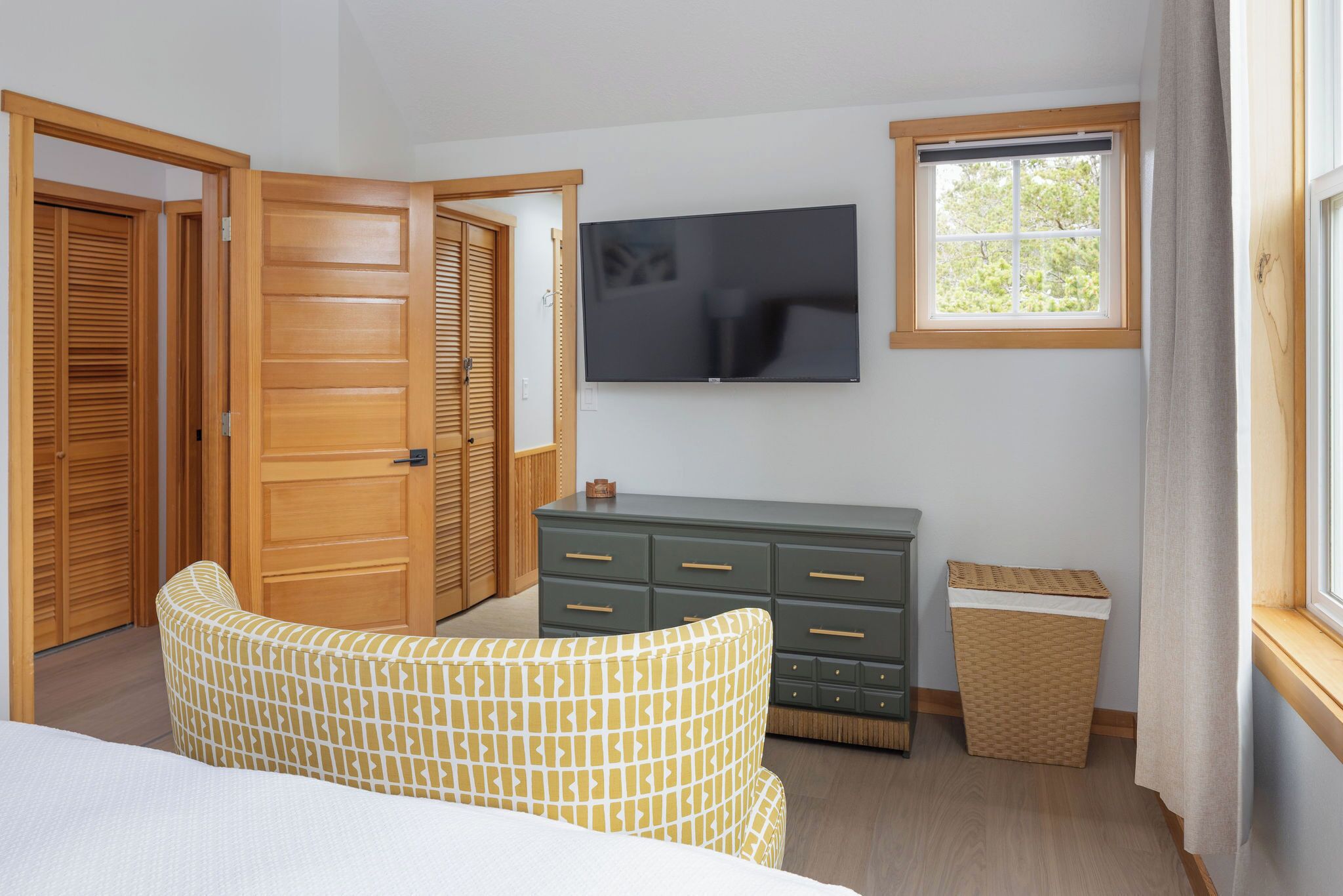 A bedroom with a bed, a dresser, a television, and a window.
