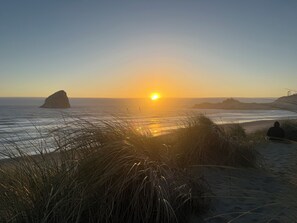 A beach with a rock formation, grass, and a person sitting on the sand. - 3 Min to Sand | Family Fun + Bunk Room | Sleeps 9 (Cloverdale)